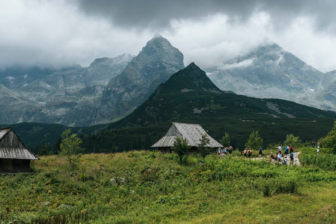 Majestic view of the Tatra Mountains with wooden cabins in Zakopane, Poland, under a cloudy sky.